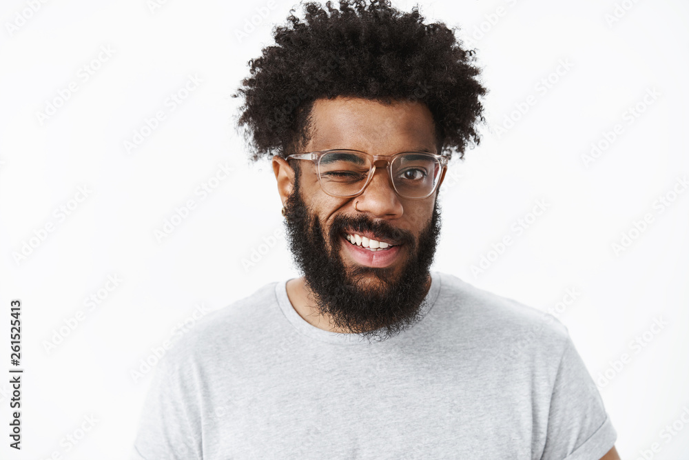 Hey smile. Portrait of optimistic and joyful handsome african american guy in good mood winking at camera friendly and grinning making positive impression, having good day over gray background Hey smile. Portrait of optimistic and joyful handsome african american guy in good mood winking at camera friendly and grinning making positive impression, having good day over gray background