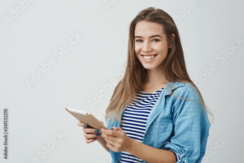 Studio shot good-looking happy tender charming young female lifestyle blogger typing new post online holding digital tablet smiling broadly giving health advices internet followers, white background