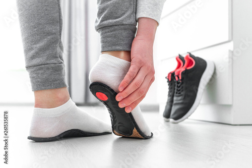 Sports woman fitting orthopedic insoles. Treatment and prevention of flat feet and foot orthopedic diseases. Foot care, feet comfort. Health care. Wearing sports comfortable shoes photo