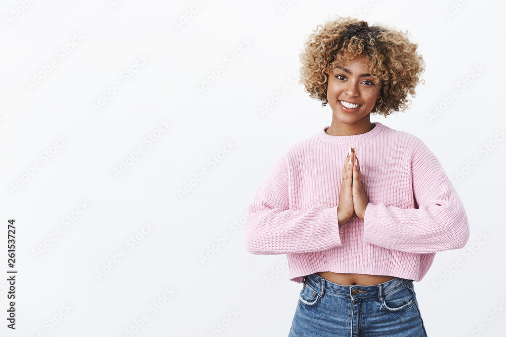 Girl expressing thanks in asian way. Portrait of charming happy african american with piercing and blond hair holding palms together over body in pray or namaste gesture smiling friendly and relaxed Girl expressing thanks in asian way. Portrait of charming happy african american with piercing and blond hair holding palms together over body in pray or namaste gesture smiling friendly and relaxed