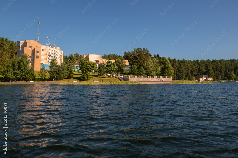 Fototapeta premium Building on the shore of a forest lake on a summer day