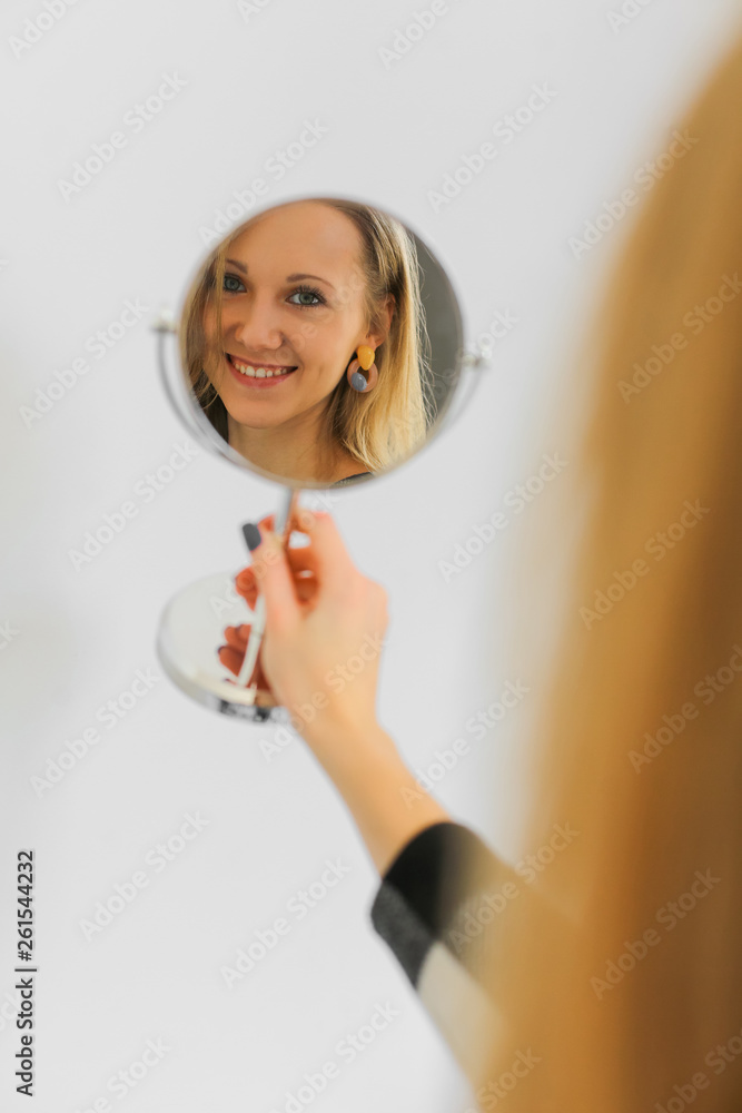 smiling positive woman is looking at her reflection in small round mirror smiling positive woman is looking at her reflection in small round mirror