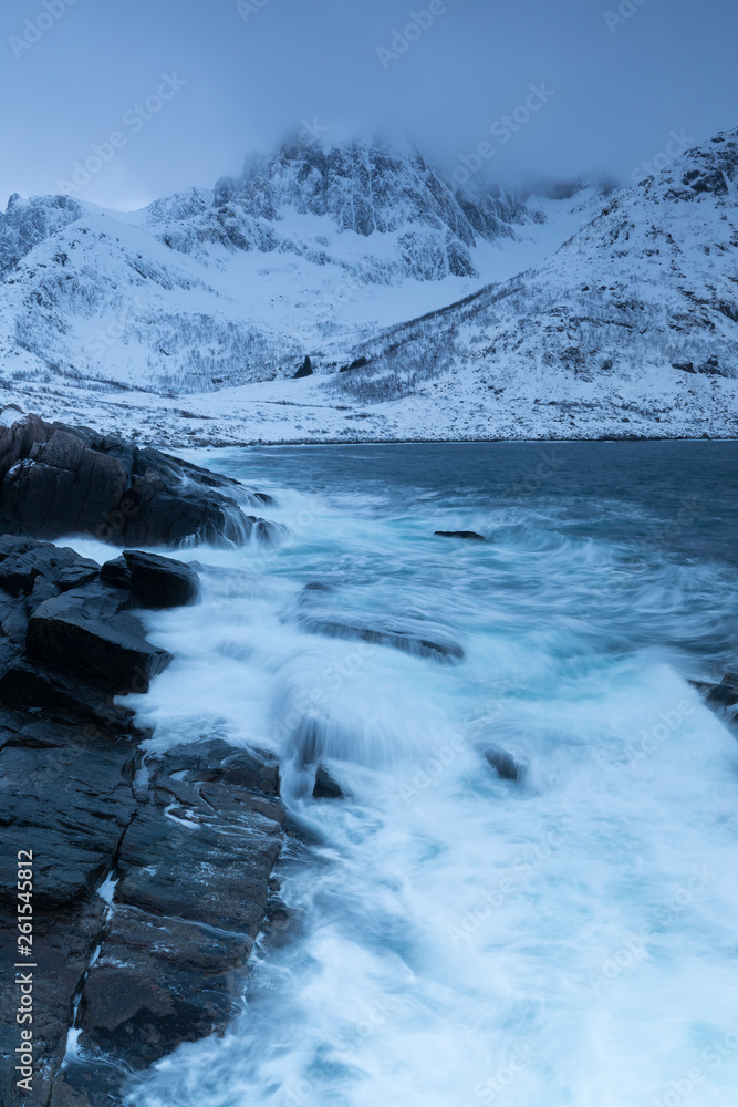 Amazing day in Mountains And Fjords, Winter Landscape, Norway Clouds sky on the Norwegian Alps and the blue hour begins in range at Senja, Norway. Beautiful christmas time near Troms county.