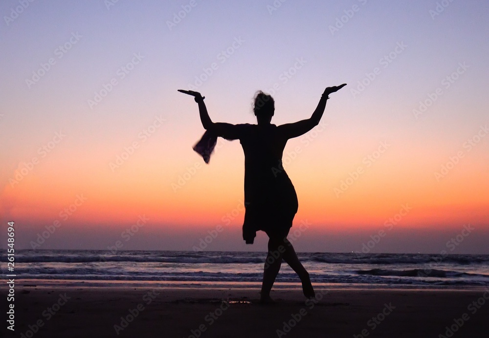Woman in Pose dancing Shiva in Sunset pink Sky near sea  in India. Dance is  useful !   Symbol of India