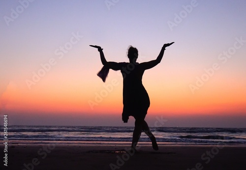 Woman in Pose dancing Shiva in Sunset pink Sky near sea in India. Dance is useful ! Symbol of India