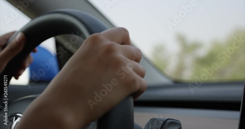Woman driving car - close up on hands turning steering wheel