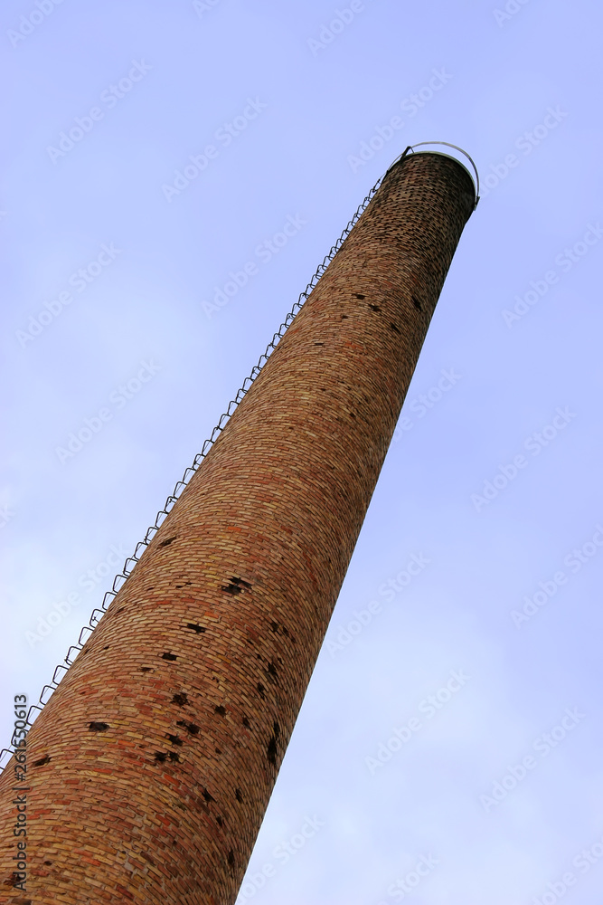 Fototapeta premium Old weathered tall industrial factory chimney, red grungy brick smokestack perspective