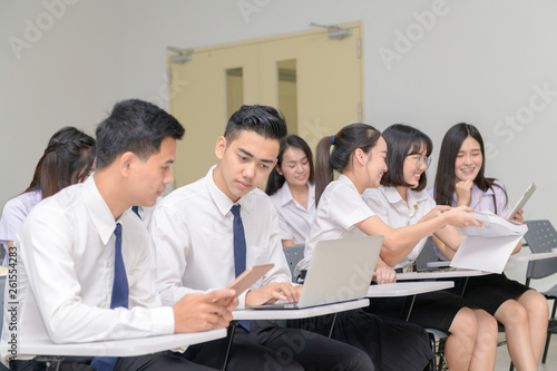 Teenage Students in uniform working with laptop in classroom
