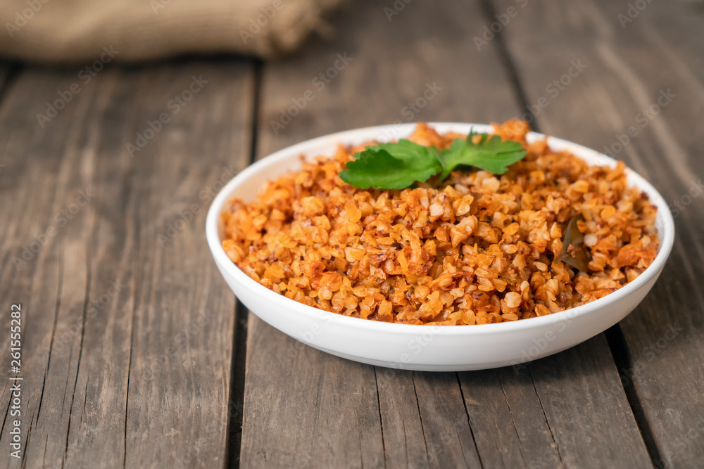 Buckwheat porridge with a sprig of parsley in a bowl on a dark rough wooden table. traditional Russian dish. Rustic style. Copy space. Buckwheat porridge with a sprig of parsley in a bowl on a dark rough wooden table. traditional Russian dish. Rustic style. Copy space.