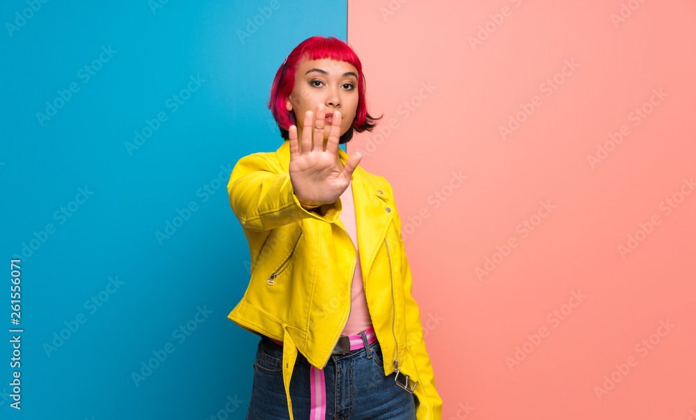 Young woman with yellow jacket making stop gesture denying a situation that thinks wrong Young woman with yellow jacket making stop gesture denying a situation that thinks wrong