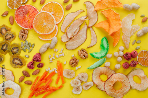 Fototapeta Naklejka Na Ścianę i Meble -  Dried fruit and vegetable chips, candied pumpkin slices, nuts and seeds on yellow background