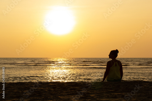 Silhouette of a young woman against the backdrop of the sunset and the big sun