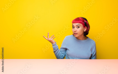 Young woman with pink hair making doubts gesture