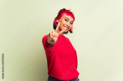 Young woman with red sweater smiling and showing victory sign