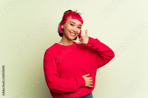 Young woman with red sweater making phone gesture. Call me back sign