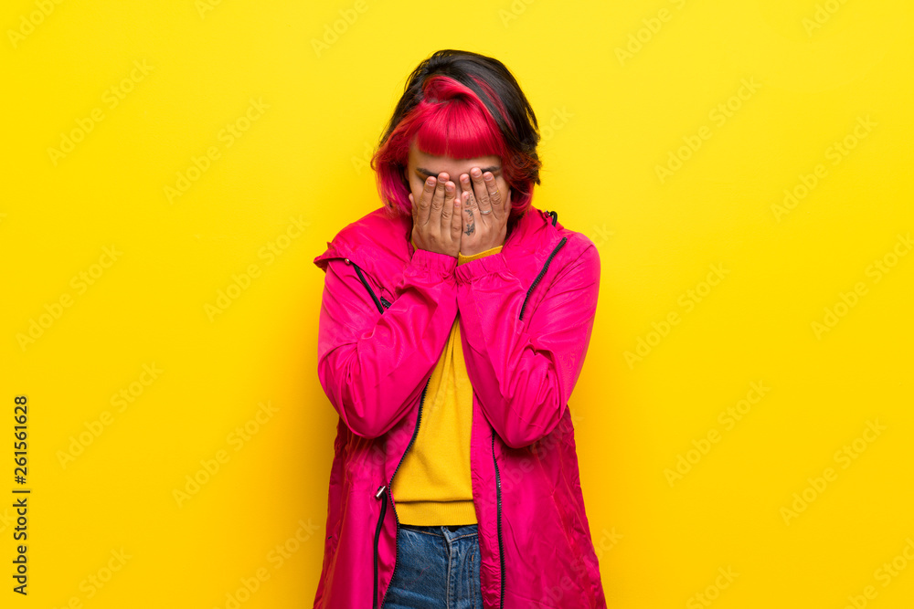 Young woman with pink hair over yellow wall with tired and sick expression Young woman with pink hair over yellow wall with tired and sick expression