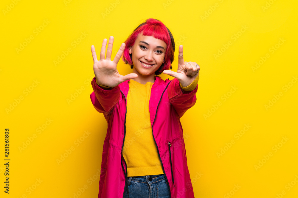 Young woman with pink hair over yellow wall counting seven with fingers Young woman with pink hair over yellow wall counting seven with fingers