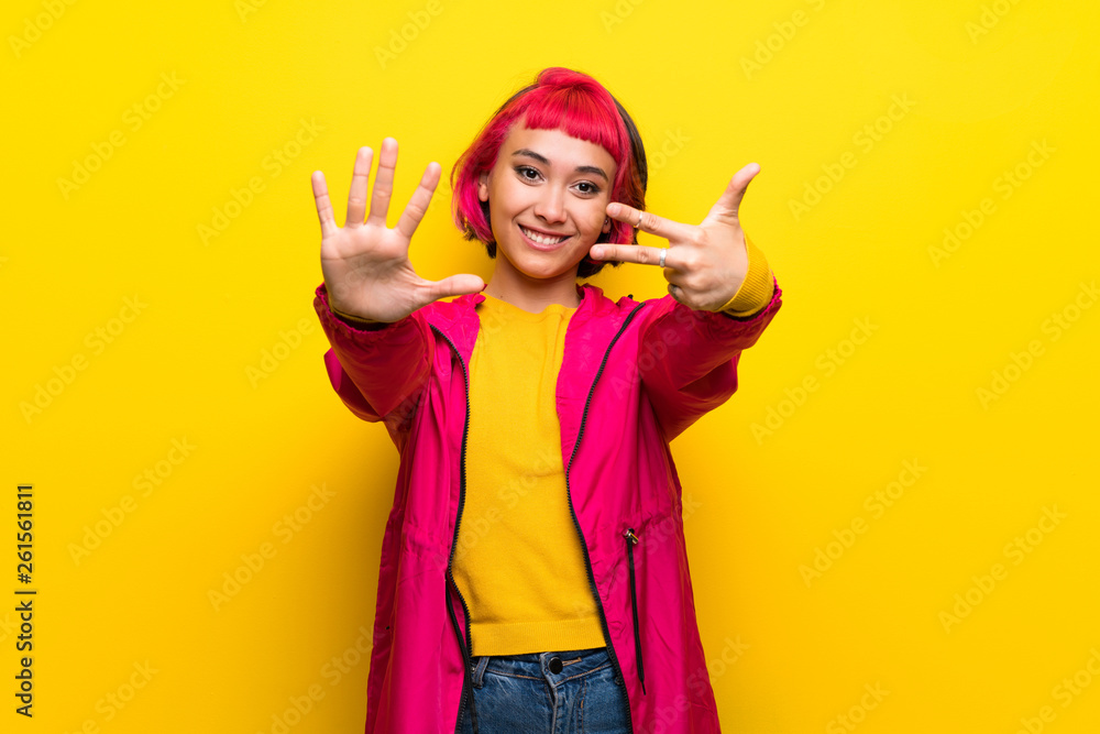 Young woman with pink hair over yellow wall counting eight with fingers Young woman with pink hair over yellow wall counting eight with fingers