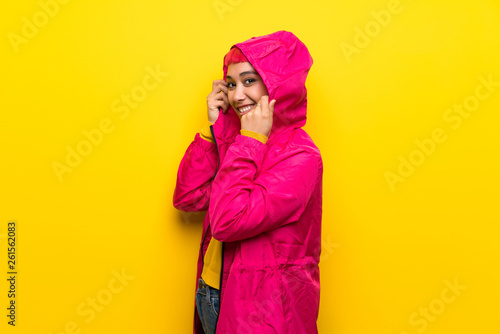 Young woman with pink hair over yellow wall .