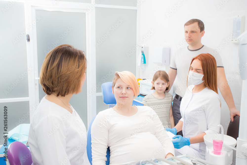 pregnant woman at the reception at the dentist, the husband and daughter are present in the office. Dental treatment for pregnant women pregnant woman at the reception at the dentist, the husband and daughter are present in the office. Dental treatment for pregnant women