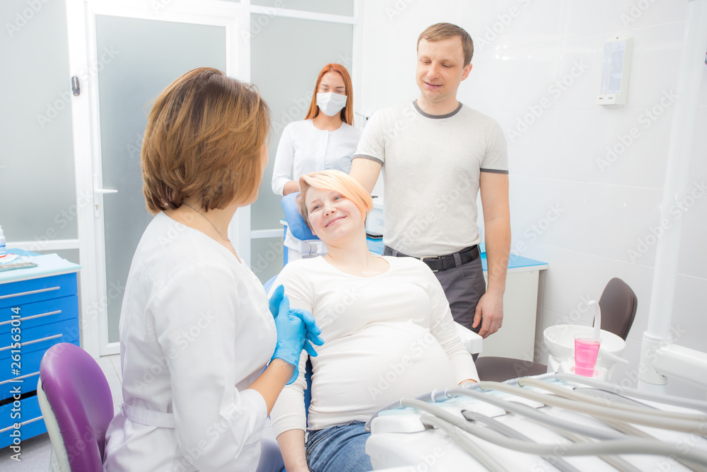 Fototapeta premium pregnant woman at the reception at the dentist, the husband are present in the office. Dental treatment for pregnant women.