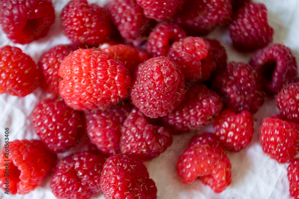Big ripe raspberries are laying on the table covered with white tablecloth Big ripe raspberries are laying on the table covered with white tablecloth