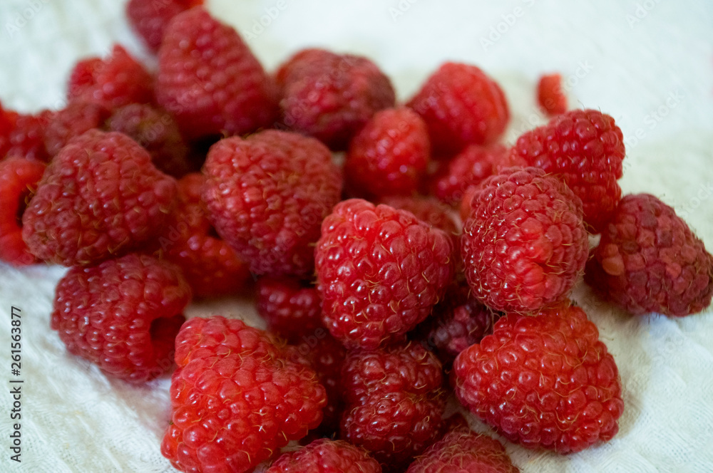 Big ripe raspberries are laying on the table covered with white tablecloth Big ripe raspberries are laying on the table covered with white tablecloth