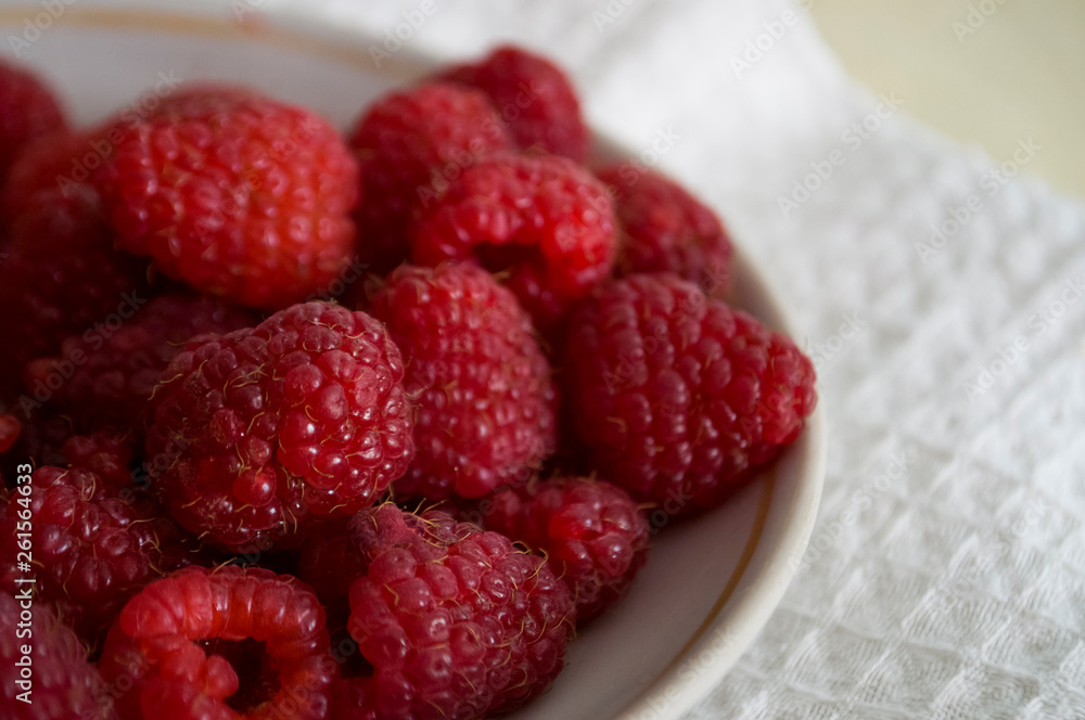 Big ripe raspberries are laying on the table covered with white tablecloth Big ripe raspberries are laying on the table covered with white tablecloth