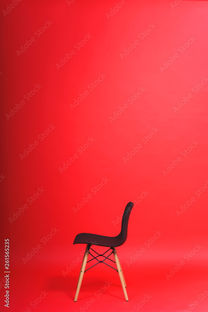 Black chair on a red background. Studio paper background. Designer chair  with a plastic back and wooden legs. Stock Photo | Adobe Stock