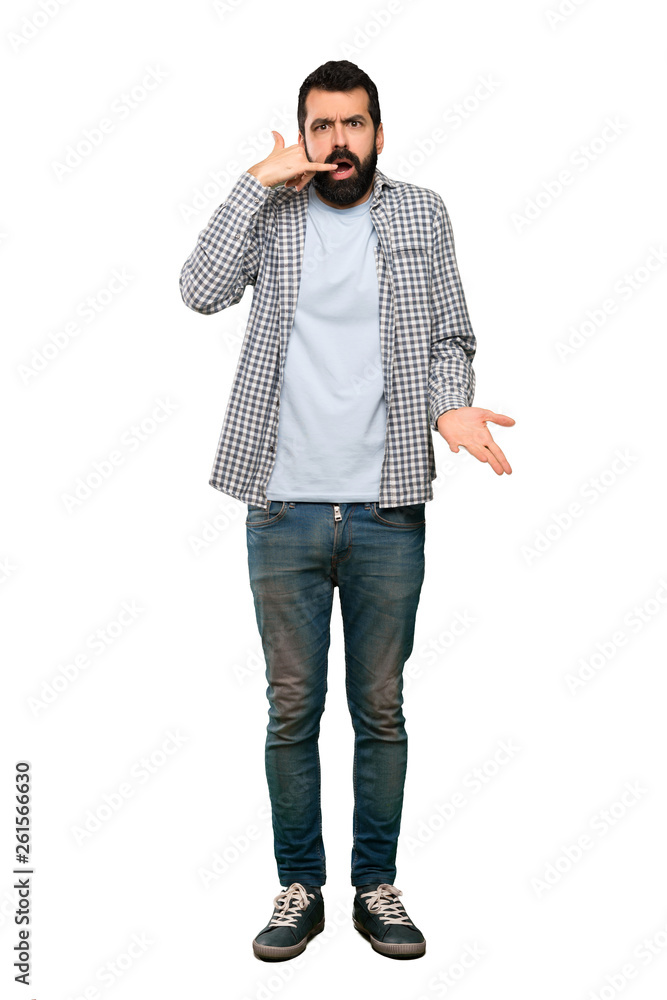 Handsome man with beard making phone gesture and doubting over isolated white background Handsome man with beard making phone gesture and doubting over isolated white background