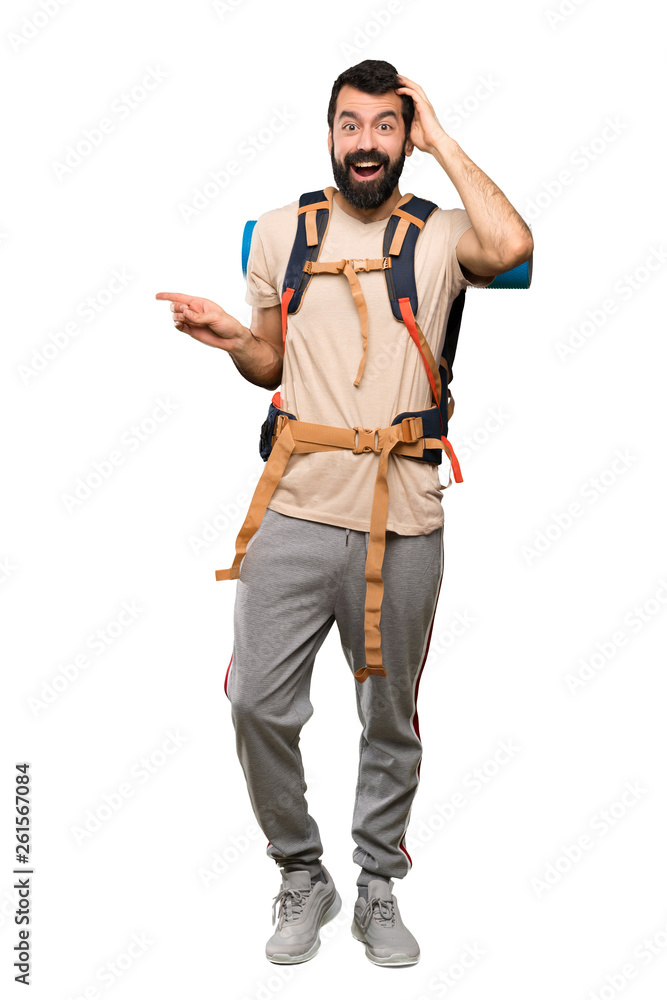 Hiker man surprised and pointing finger to the side over isolated white background Hiker man surprised and pointing finger to the side over isolated white background