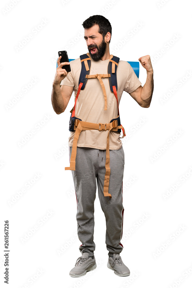 Hiker man with phone in victory position over isolated white background Hiker man with phone in victory position over isolated white background
