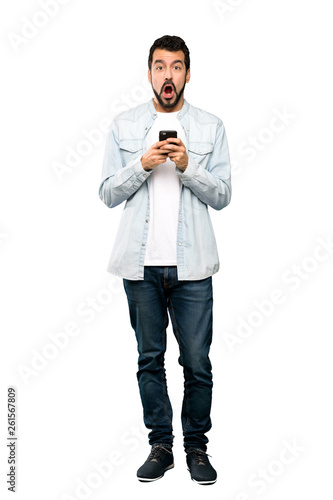 Full-length shot of Handsome man with beard surprised and sending a message over isolated white background