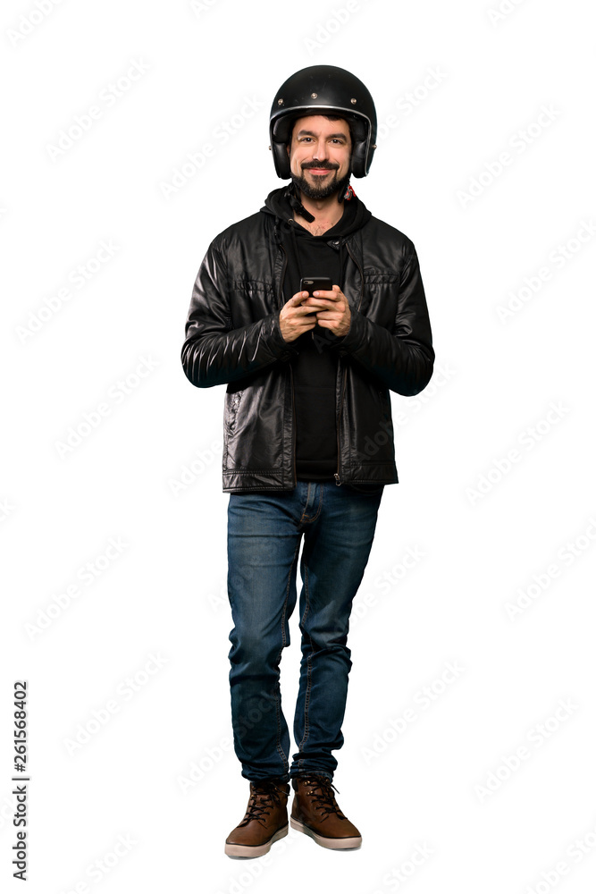 Full-length shot of Biker man sending a message with the mobile over isolated white background Full-length shot of Biker man sending a message with the mobile over isolated white background