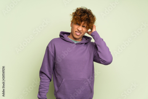 Young african american man over isolated green wall having doubts