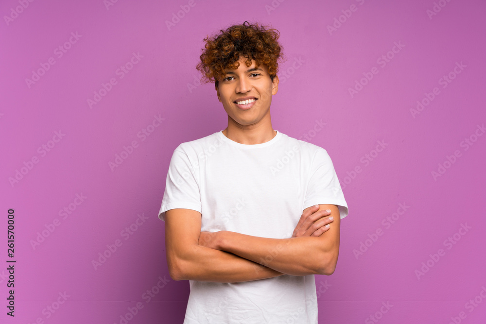 Young african american man over isolated purple wall keeping the arms crossed in frontal position Young african american man over isolated purple wall keeping the arms crossed in frontal position