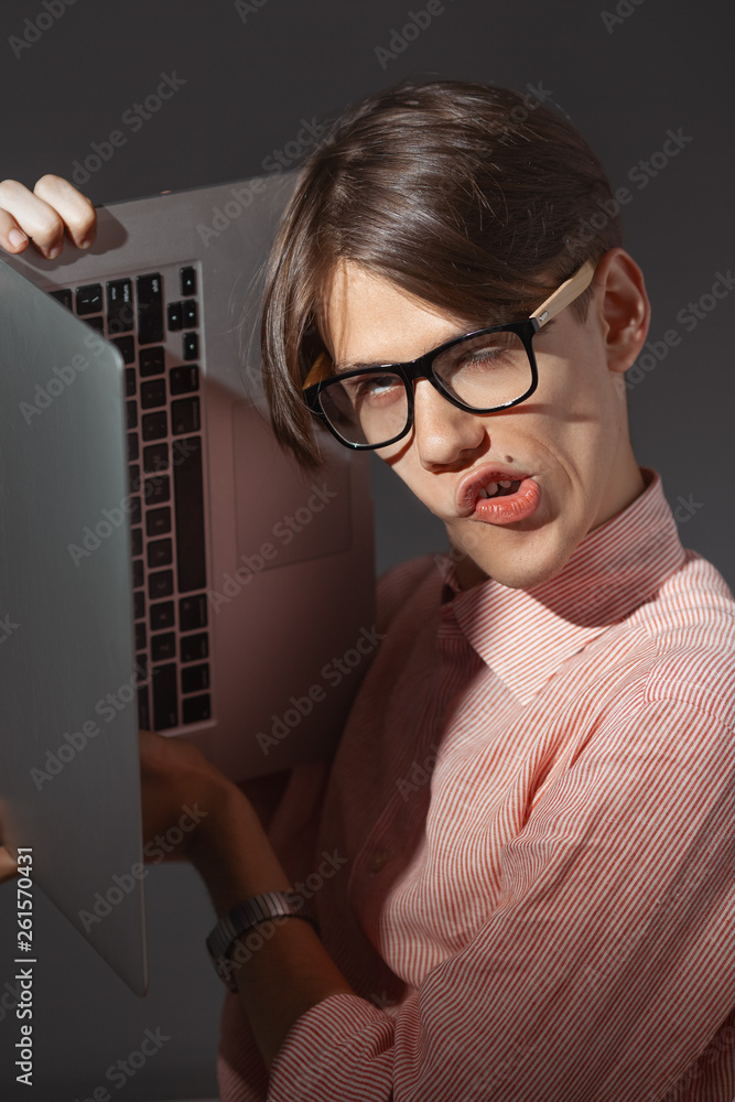 IT computer nerd. Creative teen millenial portrait indoors. Funny young man  with happy face expression in glasses hug laptop against dark background.  Internet, video game addiction concept Stock Photo | Adobe Stock