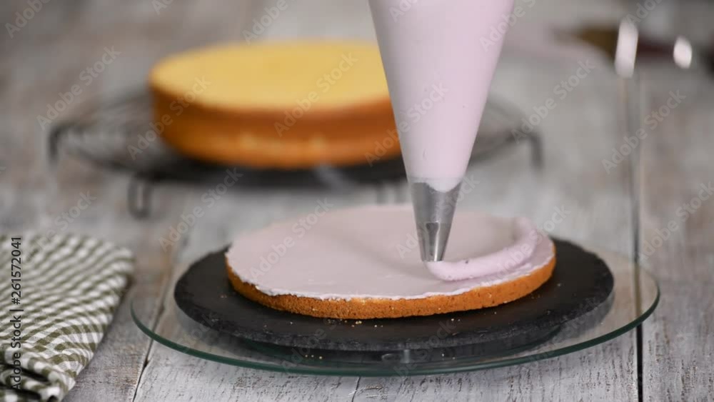 The woman's hands squeezing the cream on a cake. Tasty cream on the cake. The woman's hands squeezing the cream on a cake. Tasty cream on the cake.