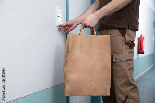 Man Ringing The Door Bell Holding Paper Bag In Hand