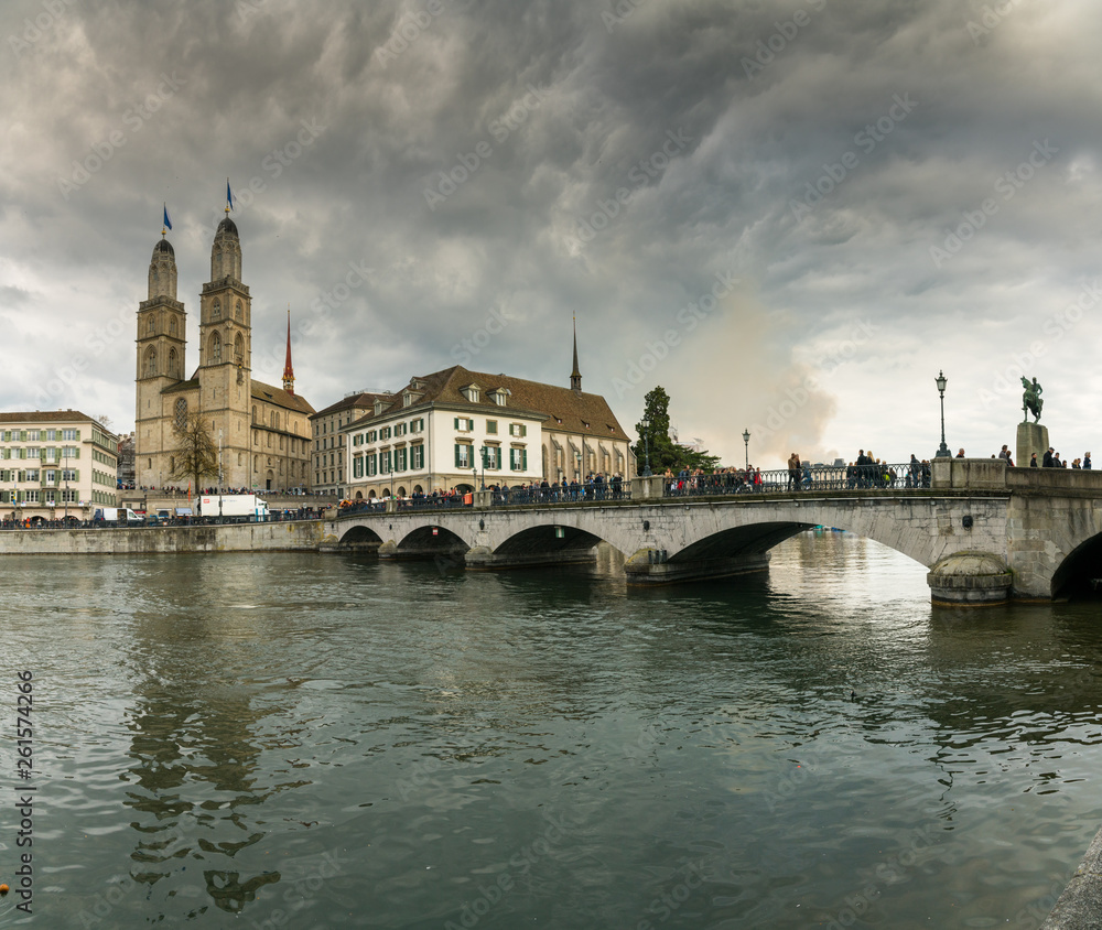 Zurich cityscape with many people crossing the river Limmat during the traditional spring festival of Sechselauten in April