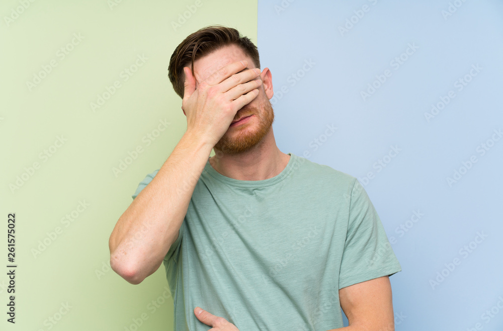 Redhead man over colorful background covering eyes by hands Redhead man over colorful background covering eyes by hands