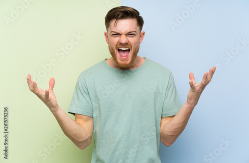 Redhead man over colorful background unhappy and frustrated with something
