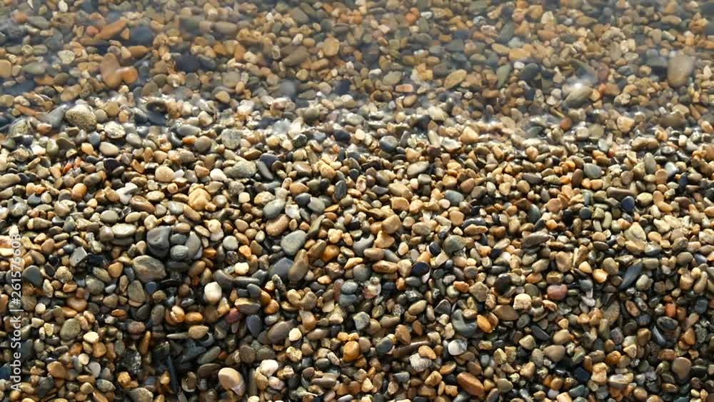 Small pebbles on the seashore is washed by water, close-up. Texture of sea pebbles. Slow motion. Small pebbles on the seashore is washed by water, close-up. Texture of sea pebbles. Slow motion.