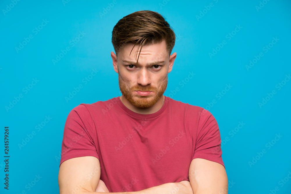 Redhead man on isolated blue wall sad Redhead man on isolated blue wall sad