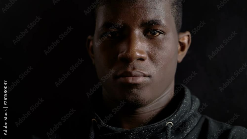 Angry confident black man alone in the dark, staring at camera Angry confident black man alone in the dark, staring at camera