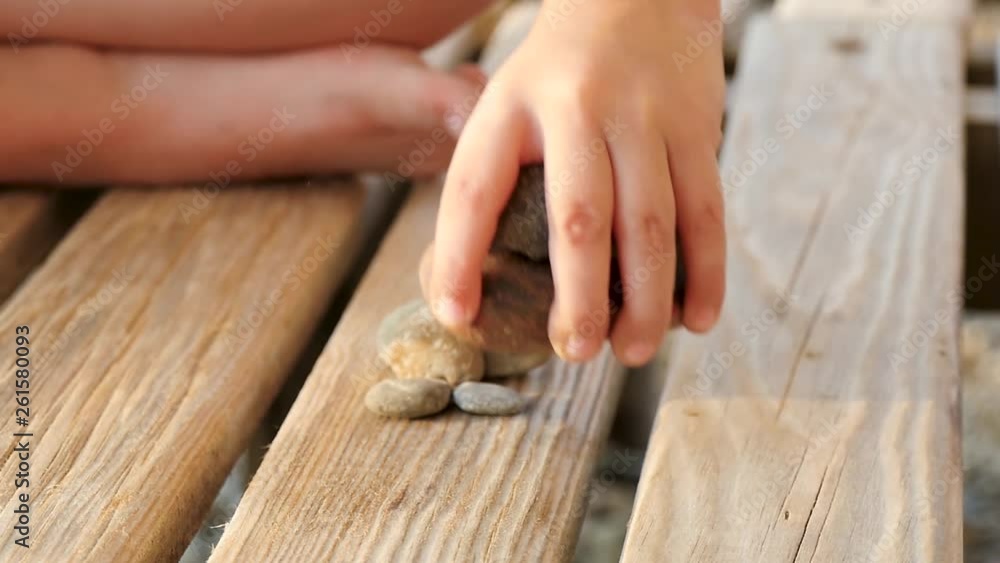 Child plays with stones on a wooden rack, the child's hand close-up. The concept of recreation and child development. Slow motion. Child plays with stones on a wooden rack, the child's hand close-up. The concept of recreation and child development. Slow motion.