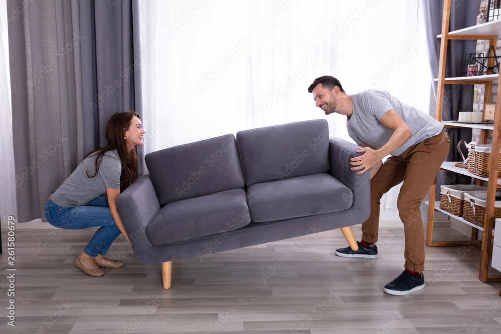 Couple Lifting Sofa In Living Room Couple Lifting Sofa In Living Room