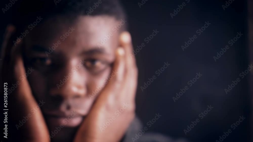 Worried thoughtful young african american man alone in the dark-change of focus Worried thoughtful young african american man alone in the dark-change of focus