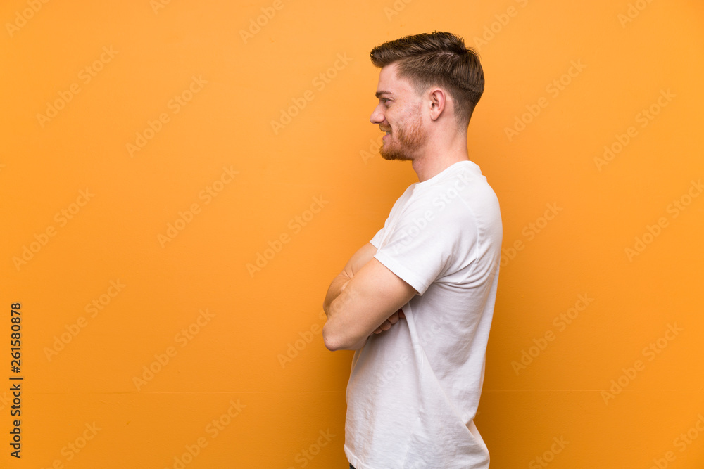 Redhead man over brown wall in lateral position Redhead man over brown wall in lateral position