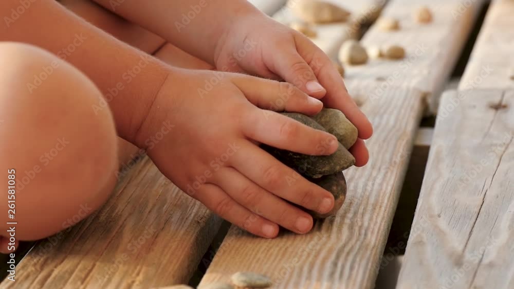 Child plays with stones on a wooden rack, the child's hands close up. The concept of recreation and child development. Slow motion. Child plays with stones on a wooden rack, the child's hands close up. The concept of recreation and child development. Slow motion.